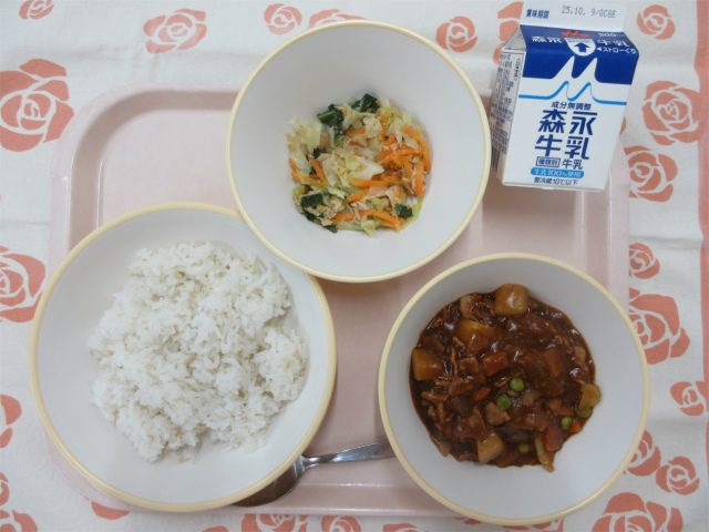 ピンクのトレーに給食が右上から反時計回りで牛乳、野菜のツナ炒め、麦入りごはん、ハヤシライスと並べられている写真