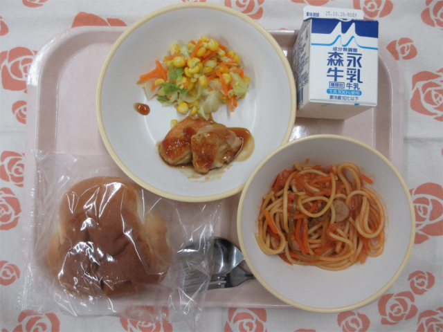 ピンクのトレーに給食が右上から反時計回りで牛乳、コーンソテー、照り焼きチキン、ロールパン、スパゲティナポリタンと並べられている写真