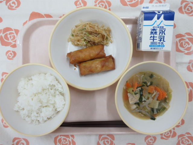 ピンクのトレーに給食が右上から反時計回りで牛乳、ピリ辛もやし、春巻き、ごはん、豚汁と並べられている写真