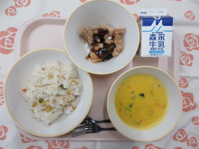 ピンクのトレーに給食が右上から反時計回りで牛乳、黒ゴマあまだれスパイシーチキン、ベジピラフ、かぼちゃのシチューと並べられている写真