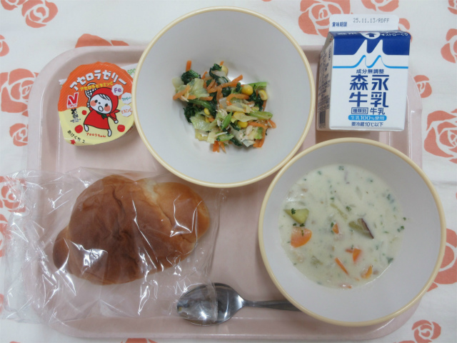 ピンクのトレーに給食が右上から反時計回りで牛乳、小松菜と鶏ささみのサラダ、アセロラゼリー、ロールパン、さつまいものクリーム煮と並べられている写真