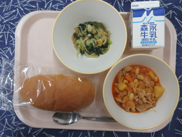 ピンクのトレーに給食が右上から反時計回りで牛乳、海藻サラダ、コッペパン、ポークビーンズと並べられている写真