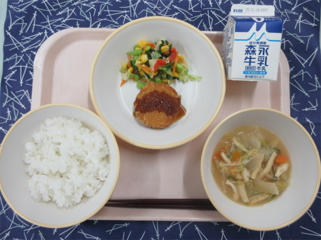 ピンクのトレーに給食が右上から反時計回りで牛乳、カラフルサラダ、キャベツメンチカツ、ごはん、白菜の味噌汁と並べられている写真