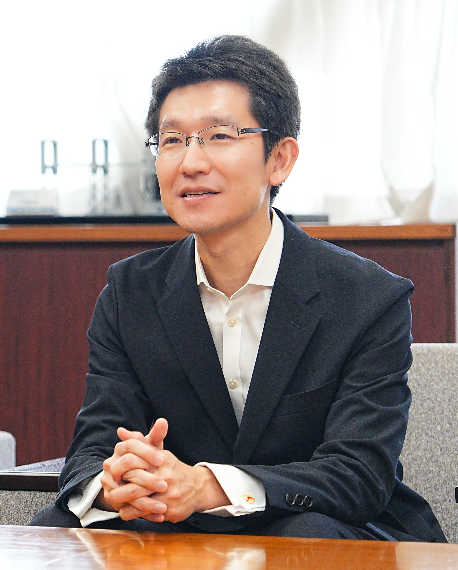 正面から写したスーツ姿の大江氏の上半身の写真