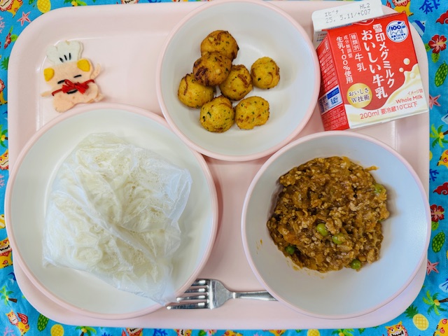 ピンクのトレーに牛乳、いとかまあげ、コック帽をかぶった布製マスコット、麺、スパゲッティミートソースと並べられている写真