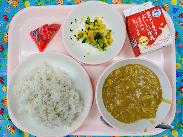 ピンクのトレーに牛乳、やさいソテー、こいボーロ、ごはん、カレーと並べられている写真