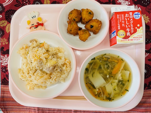 ピンクのトレーに牛乳、パンプキンボール、コック帽をかぶった布製マスコット、キムチの炊き込みご飯、ちゅうかスープと並べられている写真