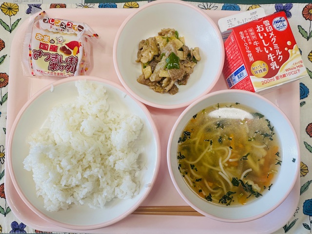 ピンクのトレーに牛乳、ぶたにくとピーマンのいためもの、さつまいもとくりのタルト、ごはん、そうめんじると並べられている写真