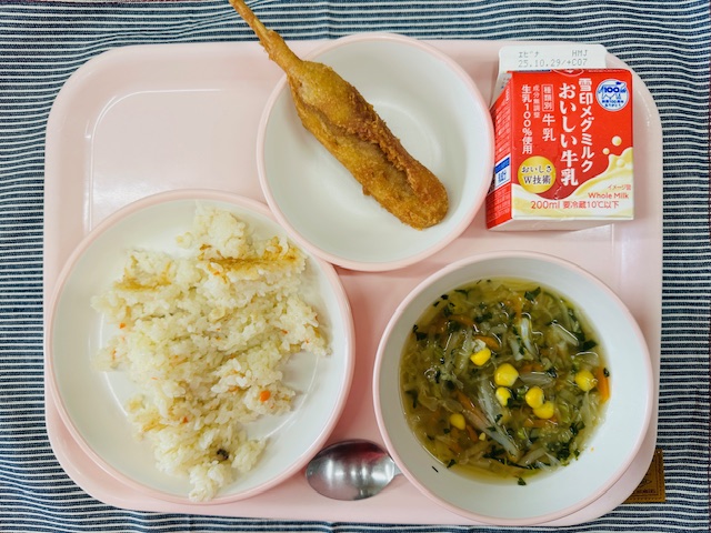 ピンクのトレーに牛乳、やさいスープ、チキンピラフ、アメリカンドッグと並べられている写真