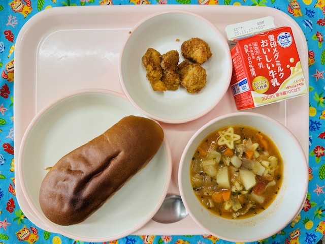 ピンクのトレーに牛乳、ステラスープ、くろぱん、チキンカツと並べられている写真