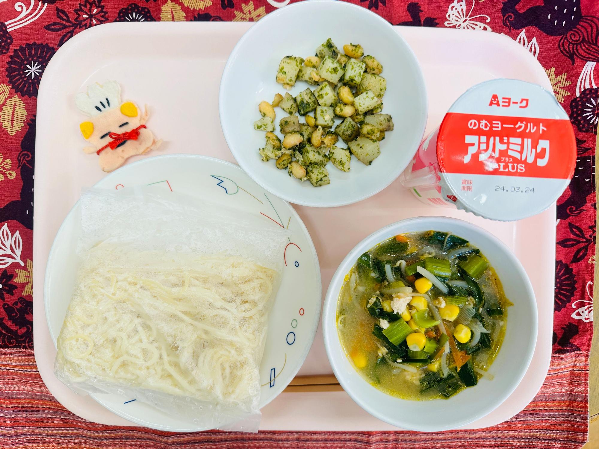 ピンクのトレーに給食が右上から反時計回りでのむヨーグルト、あおのりポテトビーンズ、コック帽をかぶった布製マスコット、めん、みそラーメンのスープと具と並べられている写真