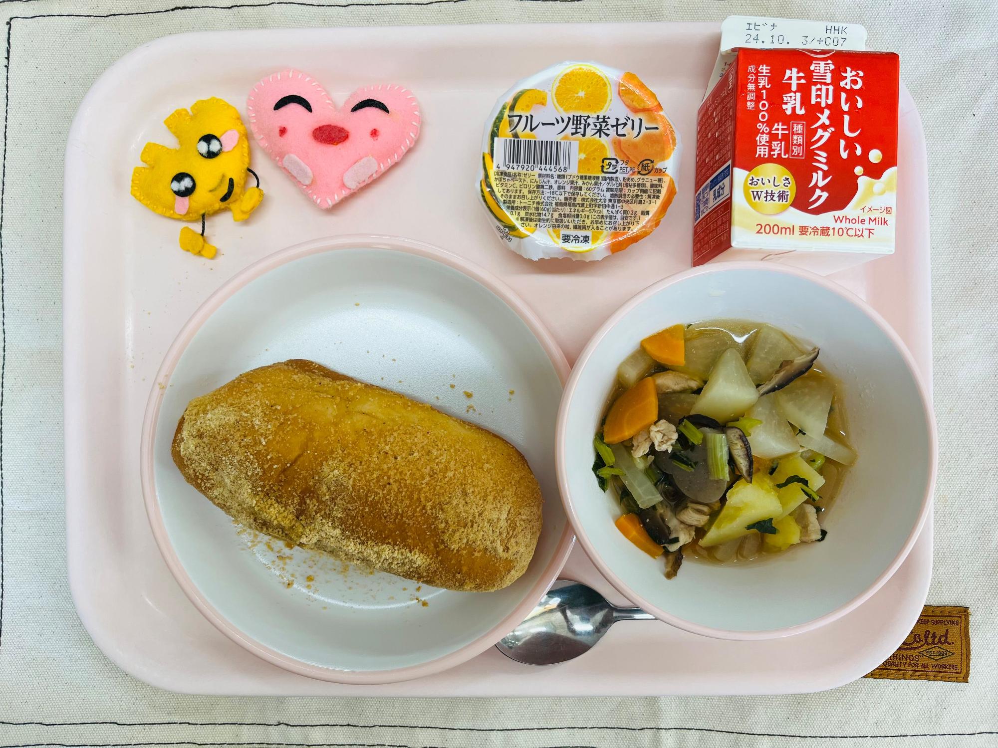 ピンクのトレーに給食が右上から反時計回りで牛乳、フルーツ野菜ゼリー、ハートの形をした黄色とピンク色の布製マスコット、きなこ揚げパン、和風ポトフと並べられている写真
