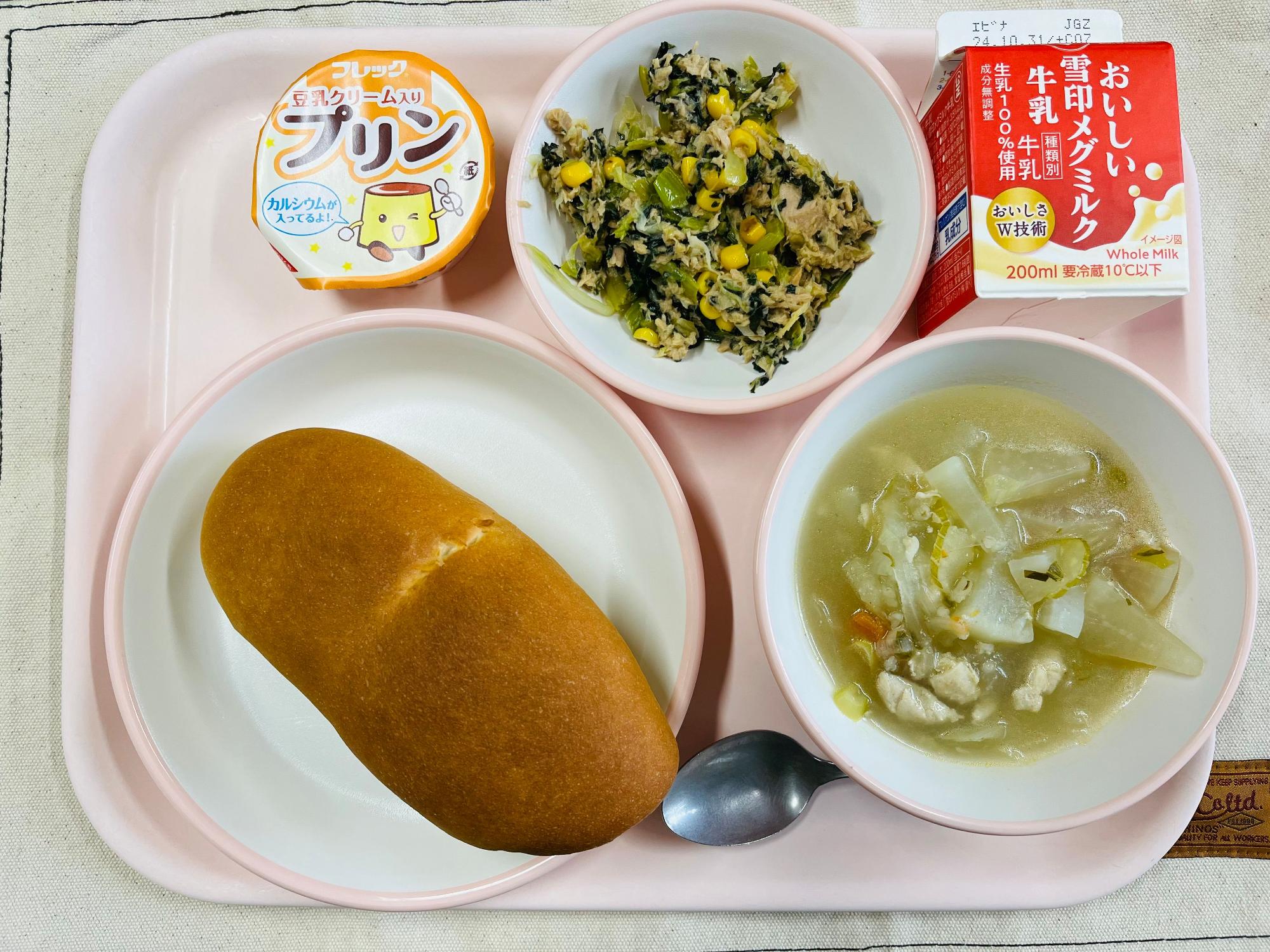 ピンクのトレーに給食が右上から反時計回りで牛乳、こまツナサラダ、豆乳プリン、ハートの形をした黄色とピンク色の布製マスコット、ソフトフランスパン、スコッチブロスと並べられている写真