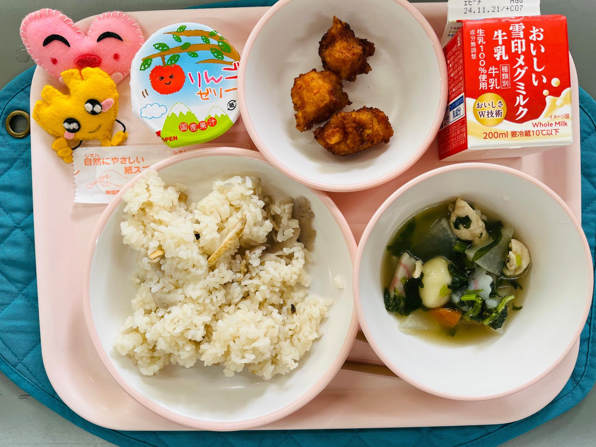 ピンクのトレーに給食が右上から反時計回りで牛乳、魚のもみじ揚げ、りんごゼリー、ハートの形をした黄色とピンク色の布製マスコット、ちらし寿司、しらたま汁と並べられている写真