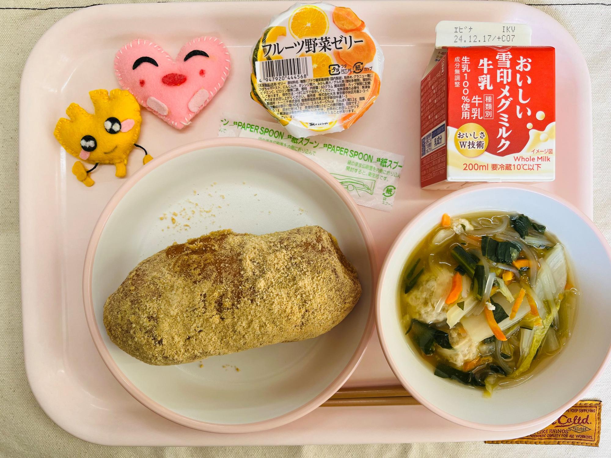 ピンクのトレーに給食が右上から反時計回りで牛乳、フルーツ野菜ゼリー、ハートの形をした黄色とピンク色の布製マスコット、きなこ揚げパン、白菜と肉団子のスープと並べられている写真