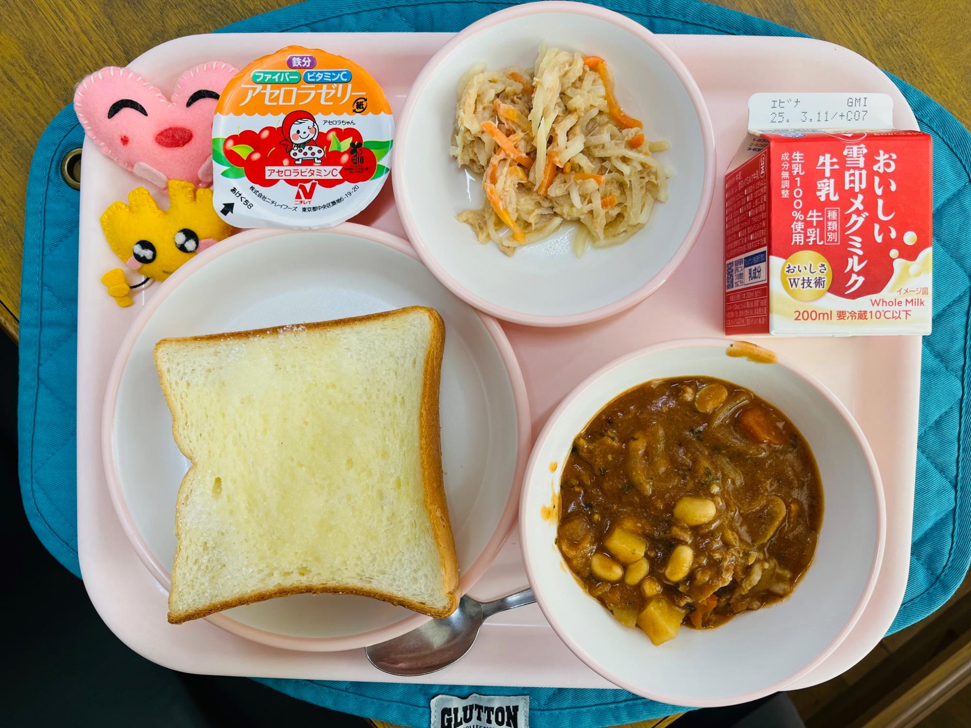 ピンクのトレーに給食が右上から反時計回りで牛乳、大根サラダ、アセロラゼリー、ハートの形をした黄色とピンク色の布製マスコット、シュガートースト、豆ストロガノフと並べられている写真