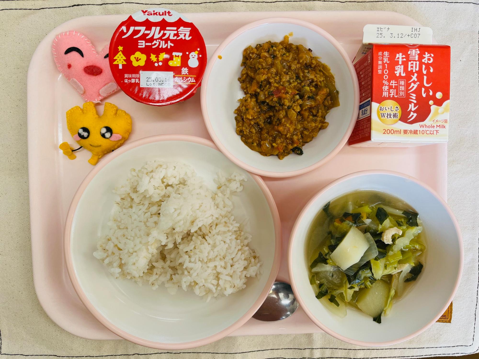 ピンクのトレーに給食が右上から反時計回りで牛乳、キーマカレー、ヨーグルト、ハートの形をした黄色とピンク色の布製マスコット、ごはん、野菜のスープ煮と並べられている写真
