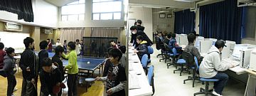 左側：体育館で卓球台を囲んでラケットを持ち卓球をしているのを複数の児童が見学している写真、右側：複数の学生が机に並んだデスクトップパソコンに向かい熱心にキーボードを操作している写真